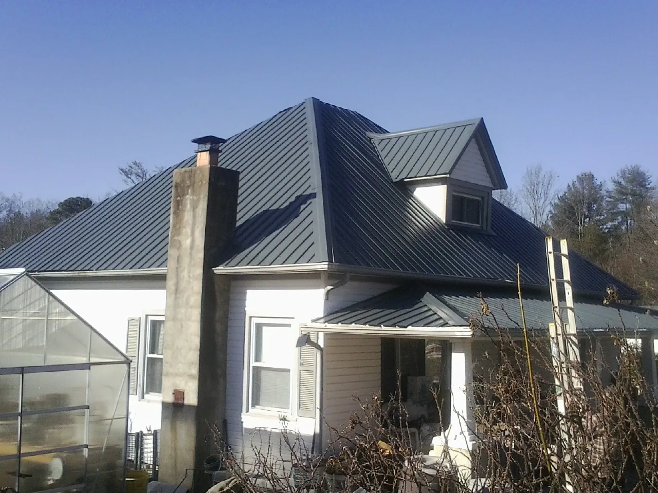 Dark blue standing seam metal roof on a white farmhouse with dormer — Slate & Tile Roof Repair by Roofing Brothers in Williamsville