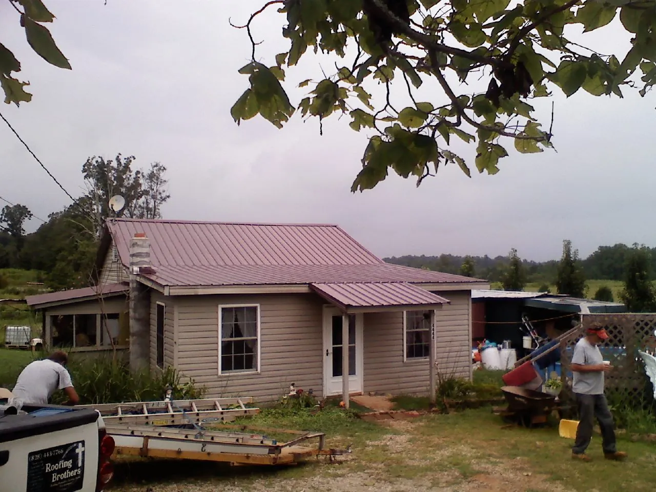 Crew finishing a mauve metal roof on a small farmhouse in Williamsville
