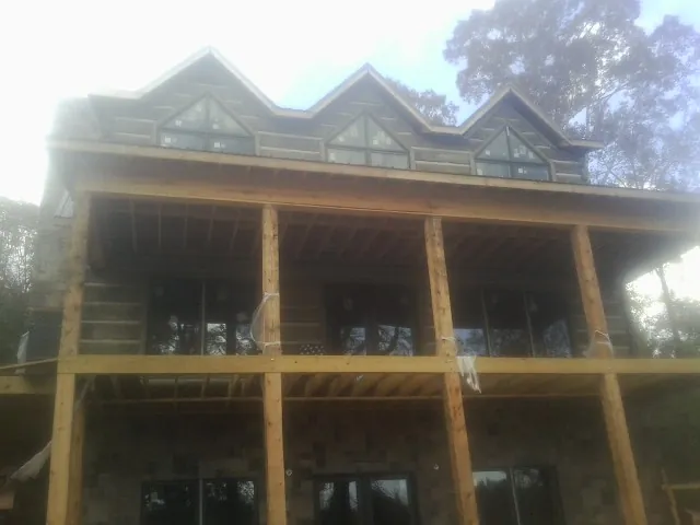 Dormers and porch framing on a large log home under construction — Roof Coating work by our crew in Williamsville